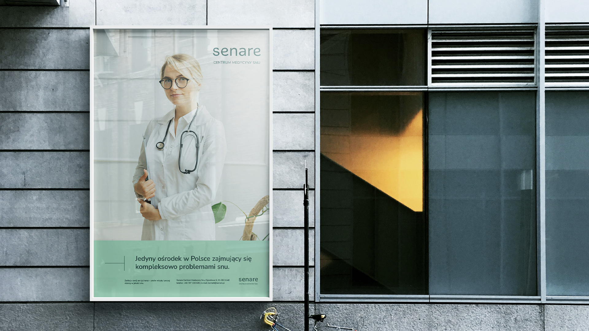 plakat na ścianie szarego budynku przedstawiający lekarkę