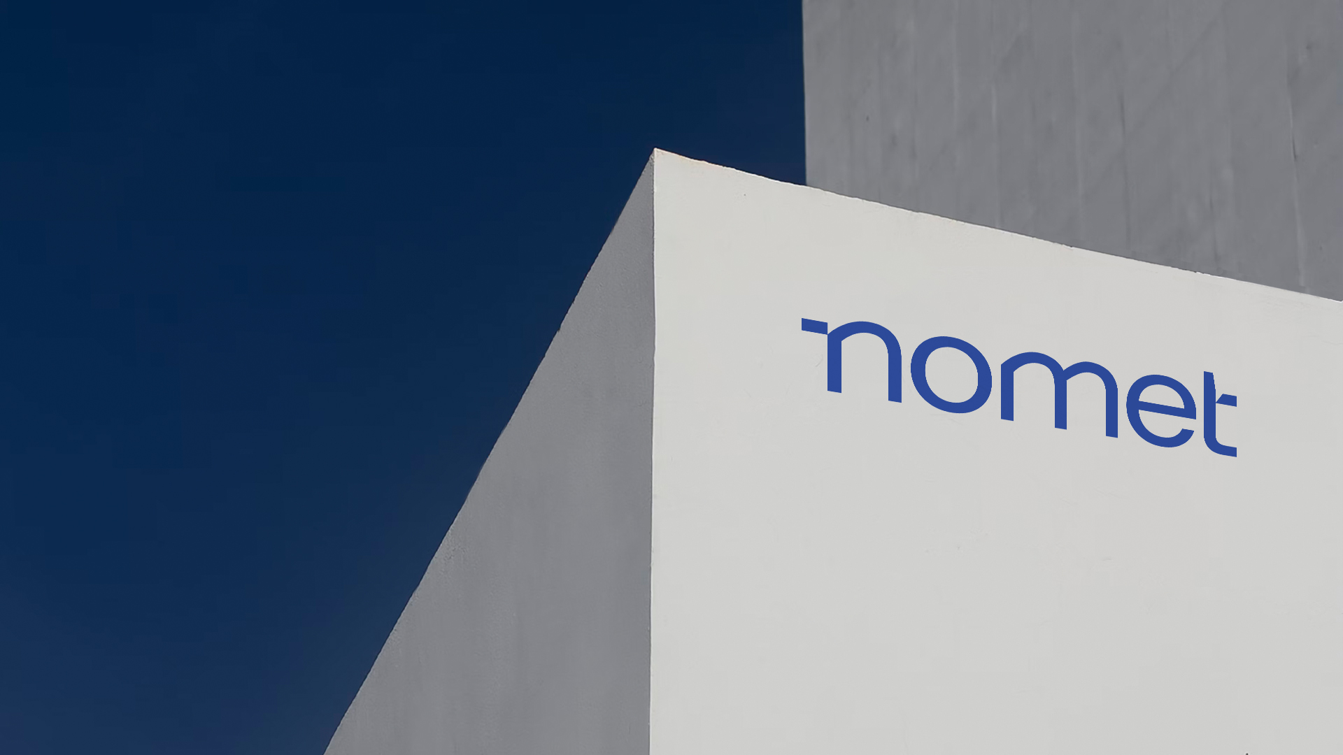 A part of a white building with blue nomet logo on a wall