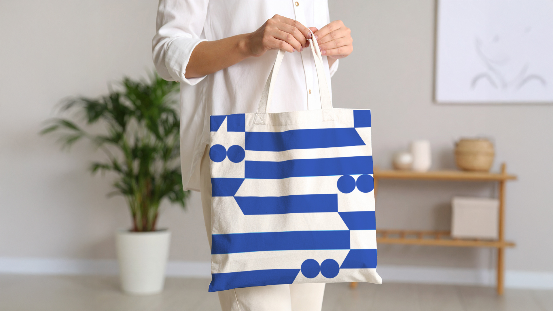 a woman in a white shirt, holding linen white bag with blue geometric pattern on it